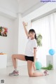 A woman in a white shirt and black shorts doing a yoga pose.