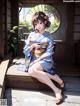 A woman in a blue kimono sitting on a porch.