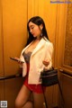 A woman in a white blazer and red skirt holding a cell phone.