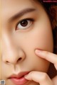 A close up of a woman's face with her hand on her cheek.