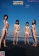 A group of women in bikinis standing on a beach.