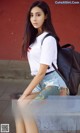 A woman sitting on a bench with a backpack.