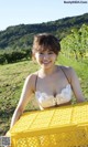 A woman in a bikini holding a yellow crate.