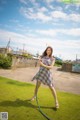 A woman in a plaid dress holding a hose.