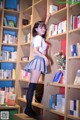 A woman standing in front of a bookshelf full of books.