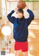 A young woman holding a basketball on her head.