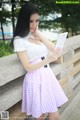 A woman in a pink and white checkered skirt holding a tablet.