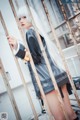 A woman with long white hair standing behind bars.