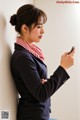 A woman leaning against a wall looking at her cell phone.