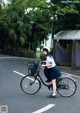 A woman riding a bike down a street with a basket on the back.